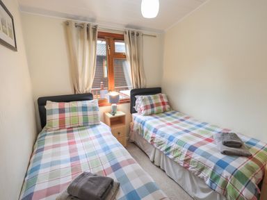 A bedroom with two single beds with plaid bedding and folded towels on each bed at Cedar Lodge in Langdale 20 White Cross Bay near Windermere