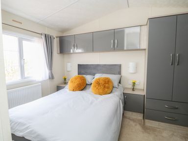 A bedroom with a bed with yellow cushions and grey cabinets at Lakeside View in Pentney near King's Lynn