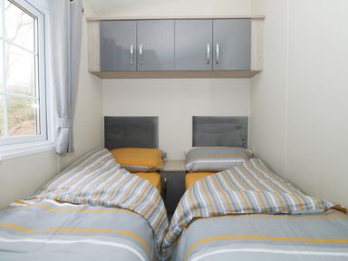A bedroom with two single beds and overhead cabinets at Lakeside View in Pentney near Kings Lynn