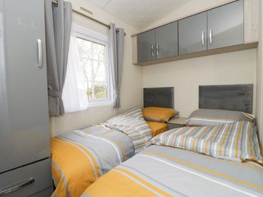 A bedroom with two single beds and overhead cabinets at Lakeside View in Pentney near Kings Lynn