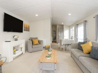 A living room with a sofa armchair coffee table and dining table at Lakeside View in Pentney near Kings Lynn