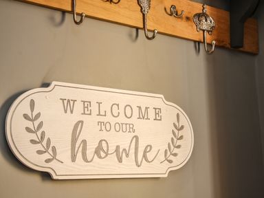 A wall with a welcome sign and decorative metal hooks on a wooden board at Sunnyside in Bircher Common near Yarpole