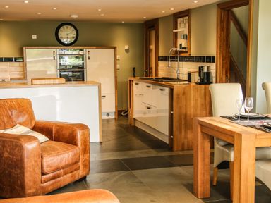A kitchen and dining area with leather armchairs wooden table white chairs and built in oven at Sunnyside in Bircher Common near Yarpole