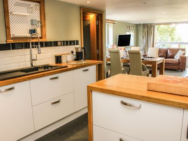 Kitchen and dining area with wooden countertops white cabinets dining table with chairs and brown sofa at Sunnyside Bircher Common near Yarpole