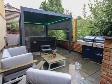An outdoor patio with seating, a hot tub under a pergola, and a barbecue grill at Sunnyside in Bircher Common near Yarpole
