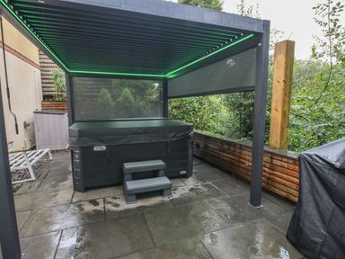 An outdoor covered area with a hot tub and steps on a stone patio at Sunnyside in Bircher Common near Yarpole
