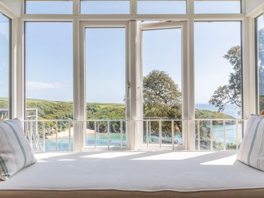 A window seat with cushions overlooking a bay surrounded by trees at Seascape in Salcombe