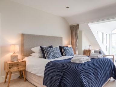 A bedroom with a bed a bedside table lamps and folded towels on the bed at Seascape in Salcombe