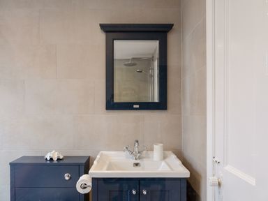 A bathroom sink with a mirror above and a cabinet with a shell on top at Seascape Salcombe