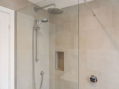 A shower area with a rain showerhead and handheld shower in a tiled bathroom at Seascape in Salcombe
