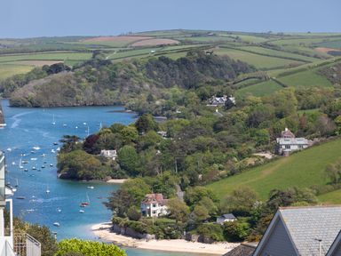 A river with boats and houses surrounded by trees and fields at Seascape in Salcombe