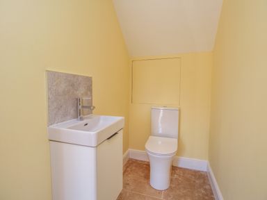 A small bathroom with a toilet and a sink against yellow walls at The Granary Burton Bradstock
