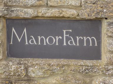 A stone wall with a rectangular plaque engraved with the words Manor Farm
