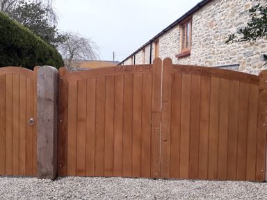 A wooden gate with the words manor farm carved at the top and a stone building in the background at The Granary Burton Bradstock