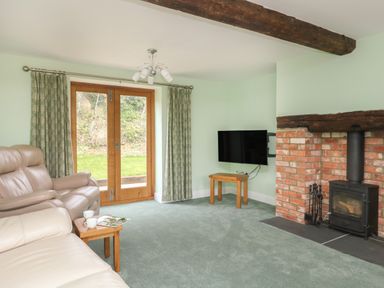 A living room with a fireplace a mounted television leather sofas and wooden doors at The Granary Burton Bradstock