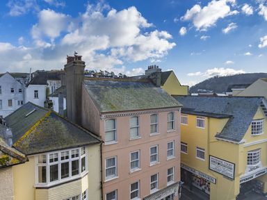 A row of old buildings with shops on the ground floor and windows above under a blue sky at Fairhaven in Dartmouth