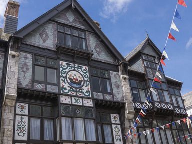 A decorative building facade with patterned tiles stained glass windows and hanging red white and blue pennant flags at Fairhaven in Dartmouth