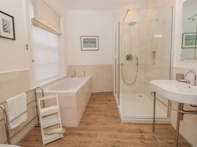 A bathroom with a bathtub shower enclosure sink towel rack and wooden floor at Fairhaven in Dartmouth