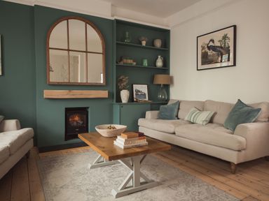 A living room with sofas a wooden coffee table a fireplace and a green accent wall at Fairhaven Dartmouth
