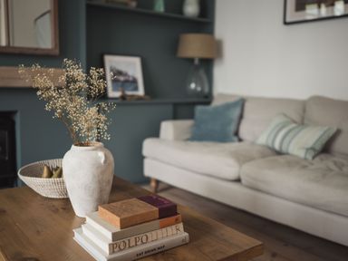 A living room with a wooden coffee table holding a vase with flowers and stacked books at Fairhaven in Dartmouth
