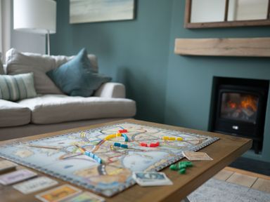 A board game set up on a wooden table in a living room with a sofa and cushions and a fireplace in the background at Fairhaven in Dartmouth