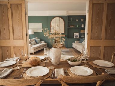A dining table set with plates glasses and cutlery next to a living room with two sofas at Fairhaven in Dartmouth