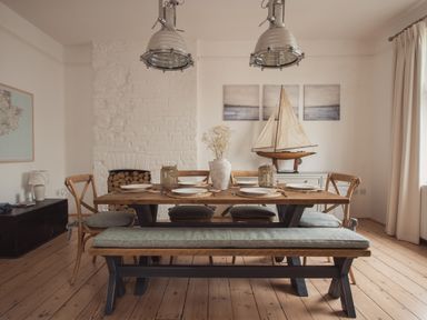 A dining room with a wooden table and chairs a bench and a model sailboat on a sideboard at Fairhaven in Dartmouth