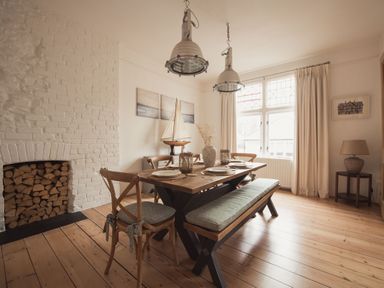 A dining room with a wooden table and benches near a window with beige curtains at Fairhaven in Dartmouth
