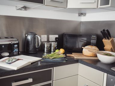 A kitchen countertop with a toaster kettle cutting board with asparagus and lemons microwave bread knife block and salad bowl at Fairhaven in Dartmouth