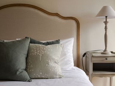A bed with green pillows and a beige headboard next to a bedside table with a lamp at Fairhaven in Dartmouth