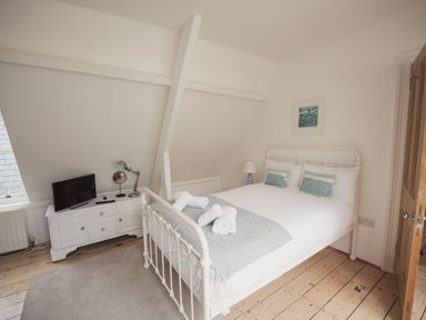 A bedroom with a bed rolled towels and a dresser with a TV at Fairhaven in Dartmouth