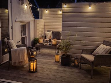An outdoor patio with wicker furniture cushions string lights and lanterns at Fairhaven in Dartmouth