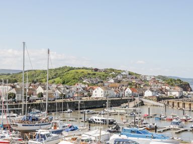 A harbor with boats docked and a town with houses and green hills in the background at The Retreat in Washford near Williton