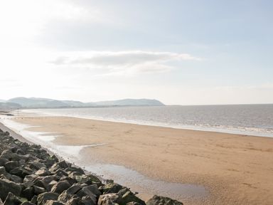 A sandy beach with rocky shoreline and hills in the background at The Retreat in Washford near Williton