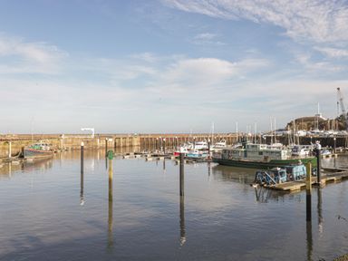 A harbor with boats docked along piers and a breakwater in the background at The Retreat in Washford near Williton