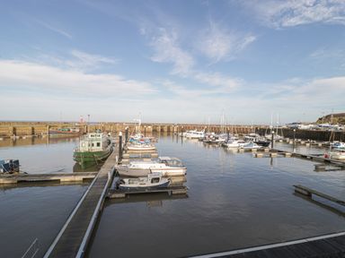 A harbor with boats docked at piers and a breakwater in the background at The Retreat in Washford near Williton