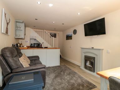 A living area with a brown sofa and pillows a fireplace and a mounted television at The Retreat in Washford near Williton