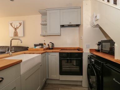 A kitchen with sink oven washing machine microwave and kettle at The Retreat in Washford near Williton