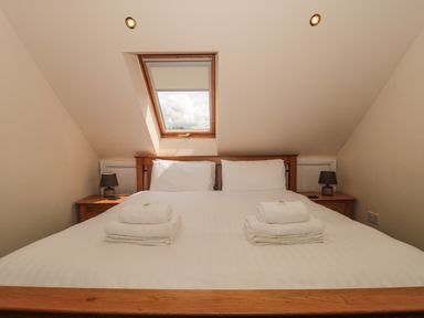 A bedroom with a double bed white towels bedside lamps and a skylight window at The Retreat in Washford near Williton