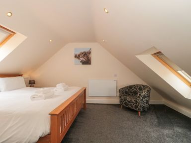 A bedroom with a wooden bed a patterned armchair and two skylight windows at The Retreat in Washford near Williton