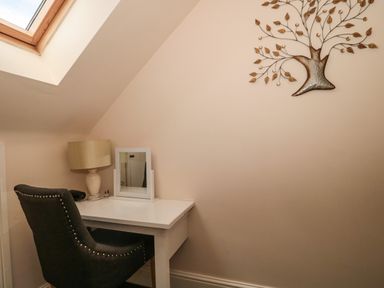 A desk with a lamp and mirror beside a black chair under a skylight window at The Retreat in Washford near Williton