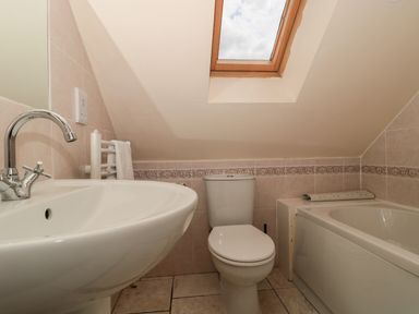 A bathroom with a sink toilet and bathtub under a skylight window at The Retreat in Washford near Williton