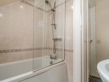 A bathroom with a bathtub shower and tiled walls at The Retreat in Washford near Williton