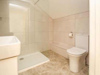 A bathroom with a toilet sink and a walk in shower at The Stables Burton Bradstock