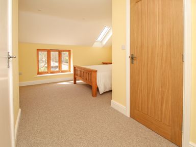 A bedroom with a wooden bed and window at The Stables Burton Bradstock