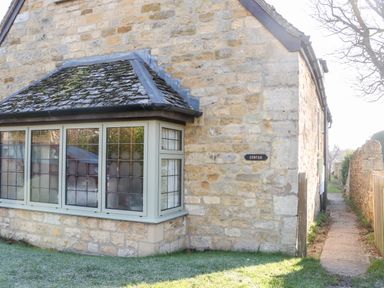 Stone cottage with leaded windows and a small path beside it at Cowfair Cottage in Chipping Campden