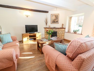 A living room with sofas and a coffee table with flowers at Cowfair Cottage in Chipping Campden