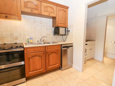 A kitchen with wooden cabinets a stainless steel oven sink and dishwasher at Cowfair Cottage in Chipping Campden