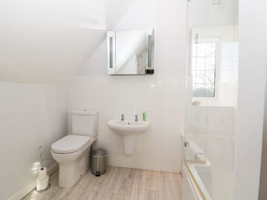 A bathroom with a toilet sink mirror and bathtub at Cowfair Cottage in Chipping Campden