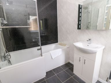 A bathroom with a bathtub and washbasin at Tynewydd Fields in Cross Inn